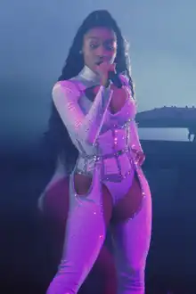 Normani stands facing forwards, singing into a microphone