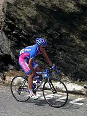 A cyclist wearing a blue and pink uniform while riding a bike.