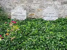 Two graves and two gravestones side by side; heading behind a bed of green leaves, bearing the remains of Vincent and Theo van&nbsp;Gogh, where they lie in the cemetery of Auvers-sur-Oise. The stone to the left bears the inscription: Ici Repose Vincent van Gogh (1853–1890) and the stone to the right reads: Ici Repose Theodore van Gogh (1857–1891)