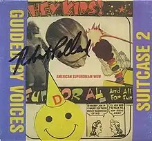 A collage with comic strip art, black-and-white photos, a jack-in-the-box, and a smiley face wearing a hat