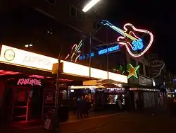 A club at night surrounded by neon signs, one of which says "Kaiserkeller"