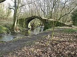 An arched stone bridge over a small beck
