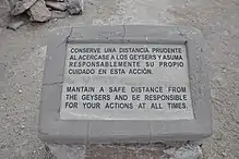 A warning sign on a rock, telling to stay away from the vents and to be responsible