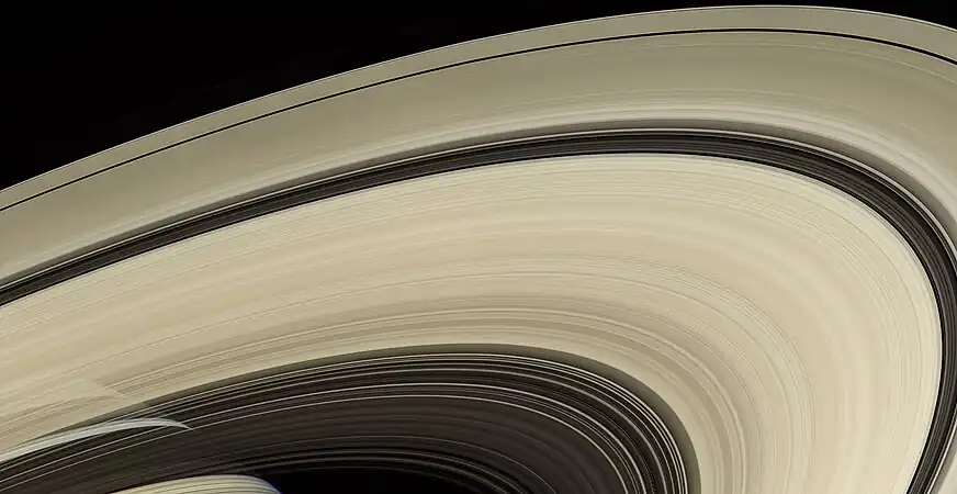 Saturn, behind the rings and draped with their shadows, as seen by Cassini from a distance of 725,000&nbsp;km (450,000 miles).