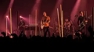 Queens of the Stone Age performing at Wembley Arena in November 2017; left to right: Dean Fertita, Josh Homme, Jon Theodore, and Michael Shuman. (Not pictured: Troy Van Leeuwen.)