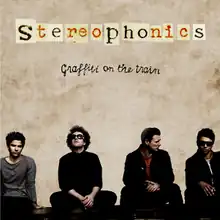 Stereophonics band members sitting alongside each other on a wall. Name of the band and album is written above them against a dull, beige wall.